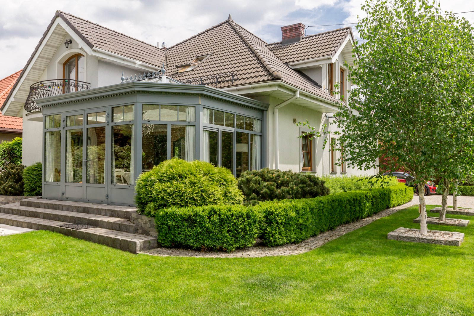 Shot of a modern house with glazed arbor, close to the garden full of green
