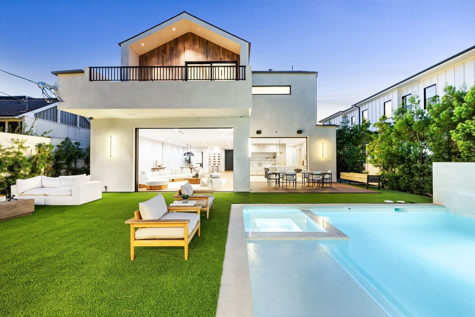 Modern luxury house with a spacious backyard featuring a swimming pool, outdoor seating, and well-maintained lawn.